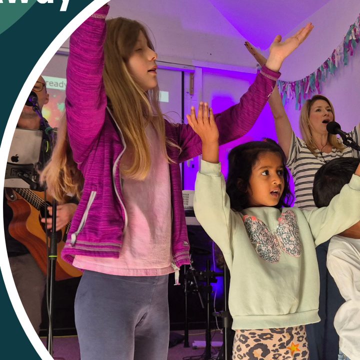 Children and adults worshipping together with hands raised