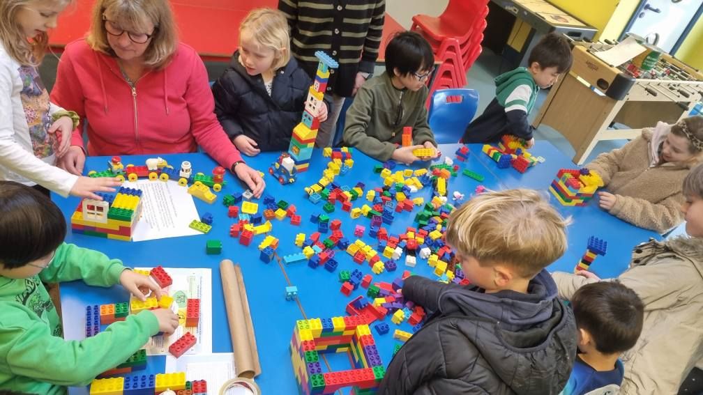 Children and adults building with Lego together around a table
