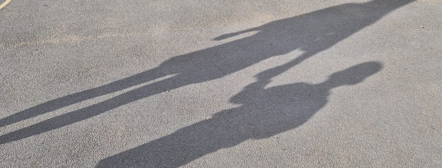 Shadows of a parent and child holding hands on the school playground