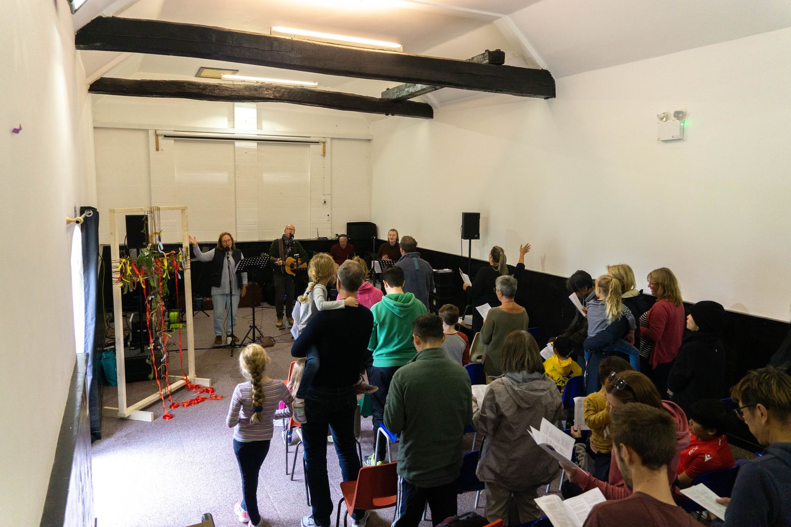 Adults and children standing together during worship at a Connect Gamston service
